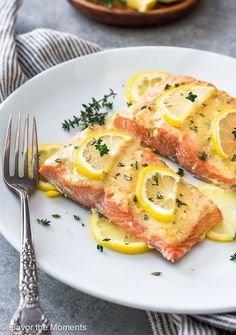 two salmon fillets with lemon and parsley on a plate next to a fork