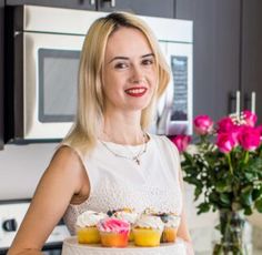 a woman standing in front of a counter with cupcakes on it