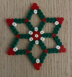 an ornament made out of buttons on a wooden surface with white, red and green beads