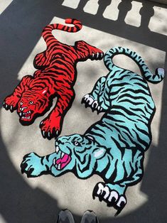 two rugs with tigers on the ground in front of a person's feet