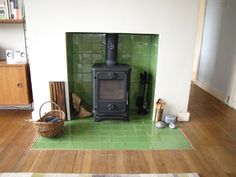 a wood burning stove sitting inside of a living room next to a green tiled wall