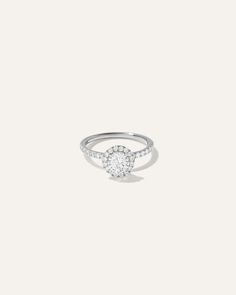 a white gold ring with diamonds on the band and an oval shaped diamond in the center