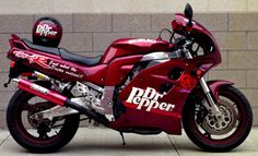 a red motorcycle parked next to a brick wall