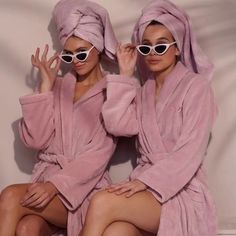 two women in bathrobes sitting next to each other with their hands on their faces