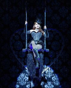 a woman sitting on top of a swing with two swords in her hand and wearing a hat