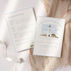 a white and blue wedding card with a lighthouse on it, next to a ribbon