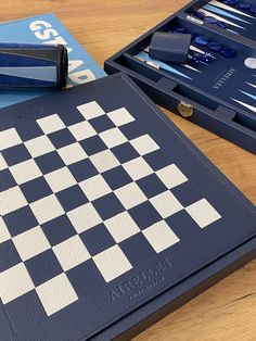 two blue and white chess boards sitting on top of a wooden table next to each other