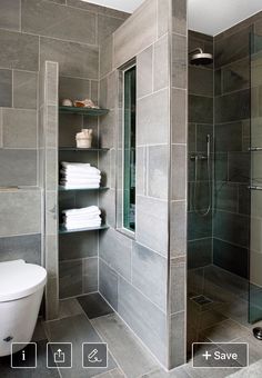 a bathroom with a toilet, shower and glass doored in area that has gray tiles on the walls