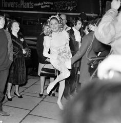 black and white photograph of woman dancing in front of crowd with cameraman behind her