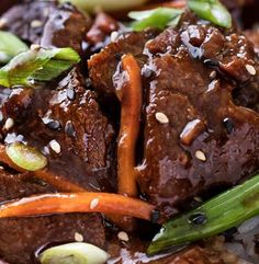 a bowl filled with beef and carrots covered in sauce, rice and sesame seeds