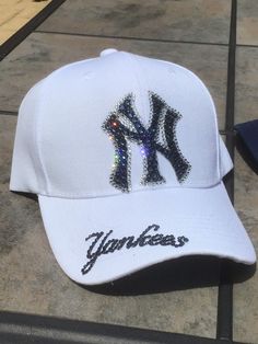 Check out these Ahhhhh-mazing Yankees hatsembellished with 100% authentic Swarovski crystal rhinestones These hats are a classic style ladies cut/fit, and have an adjustable velcro strap across the back. Choice of white or any colored hat. The white hat has navy blue stones with clear outline and the Yankees on the brim. The navy hat is made with all clear crystal and Yankees on the side of the hat I custom make these hats, and I can make them in just about any style or color combo. Please feel New York Hats Outfit, Adjustable Rhinestone Baseball Cap With Curved Brim, Adjustable Baseball Cap With Bling, White Hats With Rhinestones And Curved Brim, White Rhinestone Hat With Curved Brim, Adjustable Rhinestone Cap, White Adjustable Hat With Rhinestones, White Adjustable Rhinestone Hats, Rhinestone Baseball Cap