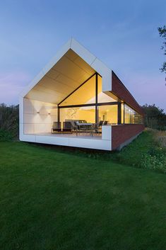 a modern house with an open roof and glass walls on the outside, overlooking a grassy area