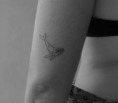 a woman's arm with a small whale tattoo on the left side of her body