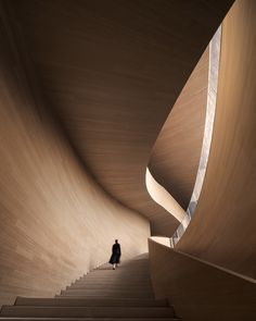 a person walking up some stairs in a building with curved wooden walls and steps leading to the upper floor