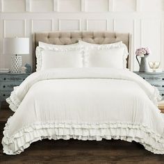 a white bed with ruffled sheets and pillows