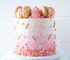 a pink cake with sprinkles and macaroons on top