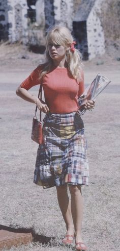 a woman in a plaid skirt is holding a magazine