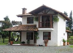 a white house with plants on the front and windows in the back, surrounded by greenery