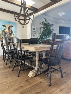 a dining room table with black chairs and a painting on the wall in the background