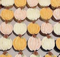 cupcakes with frosting and pumpkin decorations are arranged in rows on a table