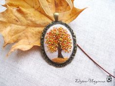 a leaf laying on top of a table next to a pendant with a tree in it