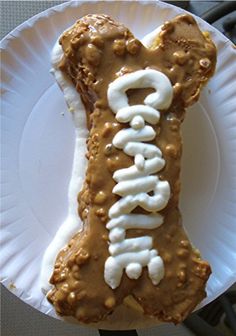 a white paper plate topped with a dog bone covered in frosting