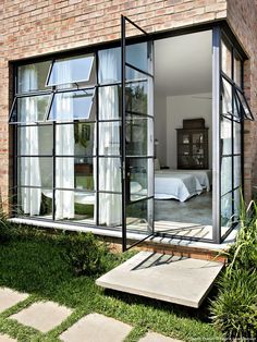 an open window on the side of a brick building with grass in front of it