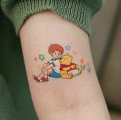 a person with a winnie the pooh tattoo on their left arm and leg, sitting next to a winnie the pooh bear