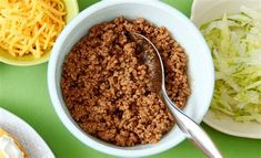 a bowl filled with ground beef next to bowls of shredded cheese and lettuce