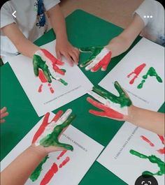 several children's hands are covered in green and red paint