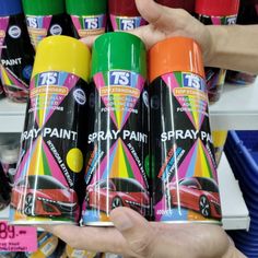 a person holding two sprays of paint in their hand