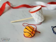 an orange basketball ball sitting on top of a table next to some knitting needles and yarn