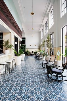 a large room with many chairs and tables in the center, along with potted plants