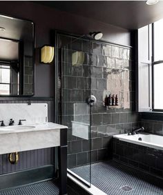 a black and white tiled bathroom with a walk in shower next to a bathtub