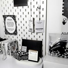 a white desk topped with lots of black and white items next to a wall mounted clock