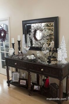 a console table with christmas decorations on it and a mirror in the corner behind it