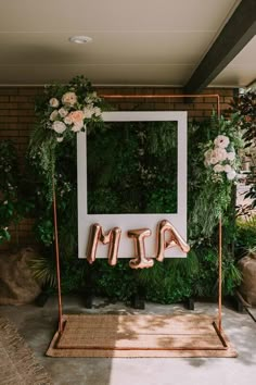 the letters are made out of copper foil and placed in front of an arch with greenery