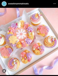 cupcakes decorated in pastel colors on a white tray with purple ribbon and pink background