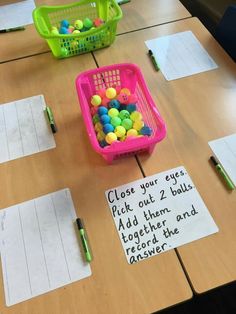 a table with two baskets filled with balls and some writing on the paper that says close your eyes pick out 2 balls add them together and record