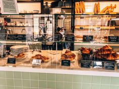 there are many different types of breads on display in the store window, including croissants and pastries