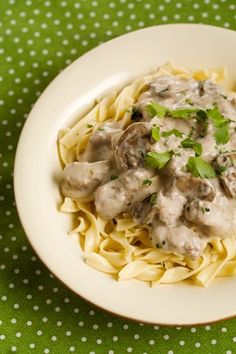 a white plate topped with pasta covered in meat and gravy on top of a green tablecloth