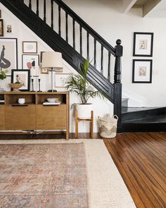 a living room with wooden floors and black railings on the stair case next to a rug