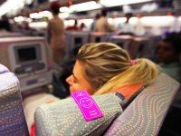 a woman is sitting on an airplane with her back turned to the camera and she has a pink sticker on her arm