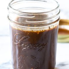 a jar filled with brown sauce sitting on top of a counter