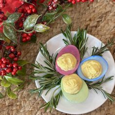 three deviled eggs on a plate with rosemary sprigs and red berries in the background