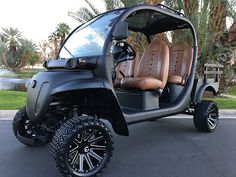 a golf cart with two seats and four wheels parked in a parking lot next to palm trees