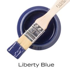 a blue paint can with a wooden brush in it and the words liberty blue on top