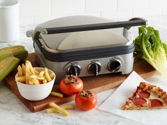 some food is laying out on a cutting board next to a sandwich and french fries