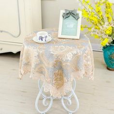 a table topped with a cup and saucer next to a vase filled with yellow flowers