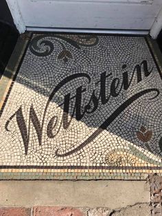 a welcome mat on the front door of a house that is decorated with mosaic tiles